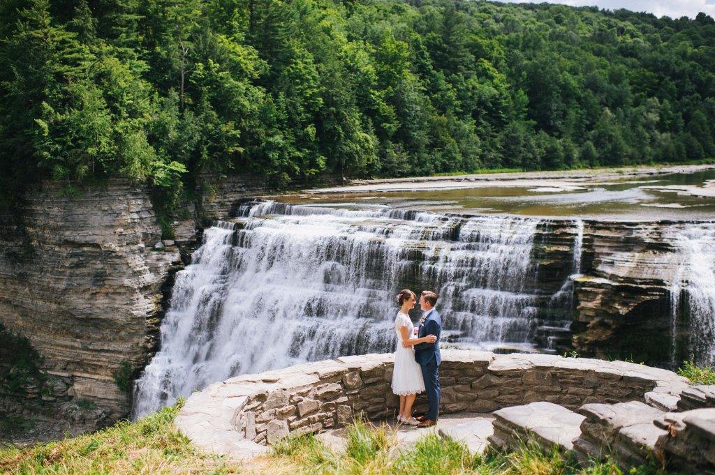couple embraces at overlook in front of waterfall