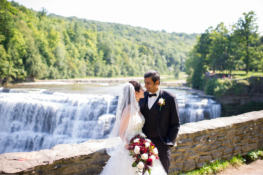 couple poses in front of waterfall on their wedding day